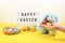 Easter composition, greeting card with child hand, toy bunny, lightbox text Happy Easter, colored decorative eggs, yellow tulips