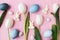 Easter composition. Stylish eggs, tulips, bunnies flat lay on pink background. Modern natural dyed blue easter eggs and white