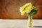 Easter concept. Bouquet of Primrose Primula with yellow flowers in glass vase on wooden backdrop. Inspirational natural floral