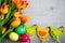 Easter concept - close up of colorful eggs, decorative chicks and tulips over wooden table