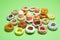 Easter concept. Collection of decorative handmade ceramic doughnuts / donuts and easter eggs on apple green background