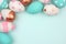 Easter corner border of pink, white, blue and rose gold eggs against a pastel blue background