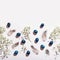 Easter creative border with quail eggs painted blue, feathers and gypsophila flowers flat lay, hard light, harsch shadows, copy