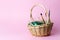 Easter decor: A simple basket of colored eggs and tassels for painting on a pink background.