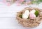Easter decor with speckled eggs, nest and pink flowers