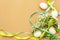 Easter decoration background. Eggs, ribbons, fresh flowers and leaves. Light matte beige backdrop