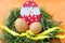 Easter decoration: yellow eggs and hand made hatched chicken in eggshell in green grass twigs nest on orange background