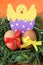 Easter decoration: yellow eggs and hand made hatched chicken in eggshell in green grass twigs nest on orange background