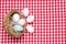 Easter eggs background. Top view on a wicker basket with colorful easter eggs on a red tablecloth or napkin. Decoration background