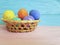 Easter eggs in a basket, straw, wooden colored springtime space