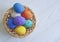 Easter eggs in a basket, straw, wooden white painted springtime space