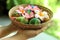 Easter eggs in a basket. Young woman holding colorful Easter eggs in a natural rattan plate, with  pink Bali frangipani flower.