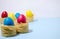 Easter eggs of blue, red, yellow color stand in pasta nests on a blue white background horizontal background