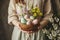 Easter eggs bowl in woman hands with flowers