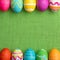 Easter Eggs, bright and colorful, in a Row on Green Burlap Background.  It`s a square photo with flat layout