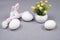 Easter eggs  bunny rabbit and spring flowers on gray background. Colors year 2021 gray and illuminating yellow