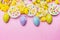 Easter eggs with cake and pretty daffodils flowers on pink background, top view