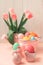Easter eggs, ceramic hen and vase with tulips on pink wooden table. Easter celebration concept. Soft focus