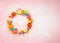 Easter eggs and colorful spring flowers made in shape of circle wreath on pastel pink background