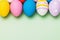 Easter eggs of different colors on a green background, top view. Holiday Template with copy space