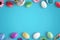 Easter eggs and flowers on blue surface. Flat lay, top view scene with free space for text