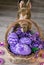 Easter eggs painted in a basket with flowers, and a soft hare in lilac tones, on wooden background