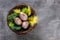 Easter eggs, painted and gold foiled, in a nest with green and yellow feathers. Traditional easter decoration on a grundge granite