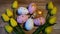 Easter eggs in pastel shades surrounded by yellow tulips