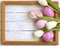 Easter eggs, photo frame, tulips on a white wooden background