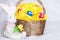 Easter eggs on pompom in basket and toy rabbit on checkered whit