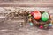 Easter eggs in small nest and willow branch on wooden background