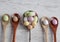 Easter eggs - speckled and sugar coated on wooden and silver spoons on white rustic wooden table, top view.