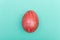 Easter Eggs on turquoise background. Red egg handmade new style of colouring form flower on a colored cardboard. Pattern, easter c