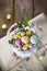 Easter eggs in the white basket on rustic wooden background