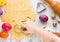 Easter food concept. Kid hands cut cookie from raw dough on a white table