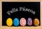 Easter frame with painted eggs and chalkboard. Happy Easter in white chalk. Happy Easter in portuguese : feliz pÃ¡scoa