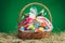 Easter gift basket with multicolor eggs, green background