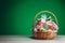 Easter gift basket with multicolor eggs, green background