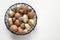 Easter golden, quail, chicken eggs in modern black bowl on white. View from above. Close up. Space for text