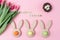 Easter holiday background with colored eggs in bunny ears shaped egg cups, pink flowers tulip , Happy Easter wooden