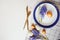 Easter holiday festive dining table with plate, golden cutlery, painted eggs and hyacinth flower on white background