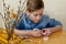 Easter Holiday at Home. Young blonde boy coloring drawing Easter Eggs