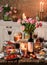 Easter holidays table, wine glasses, Easter cake, color eggs, baked meat with vegetables, flowers and candles for festive dinner