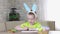 Easter kids. A happy boy with rabbit ears on his head smiles, plays at home with colored eggs and draws. Preparing for Easters the