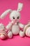 Easter knitted rabbit with a painted egg on a pink background. Concept of the Easter holiday.ok