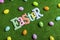 Easter letters banner on artificial grass with scattered plastic eggs