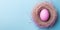 Easter pink egg in a nest, top view, pastel blue background