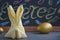 Easter.  Rabbit folded serving napkin and easter golden egg on dark blackboard background with text