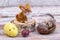 Easter rabbit on a stump with Easter eggs in a basket with feathers