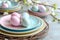 Easter rainbow pastel table setting for dinner with ceramic plates, blossom and easter eggs